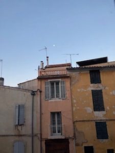 Pale pink and gold houses under an early morning blue sky.