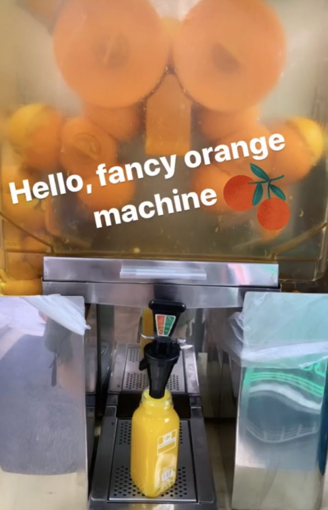 A machine that squeezes oranges to fill a disposable plastic bottle with fresh orange juice. The photo says: Hello, fancy orange machine 