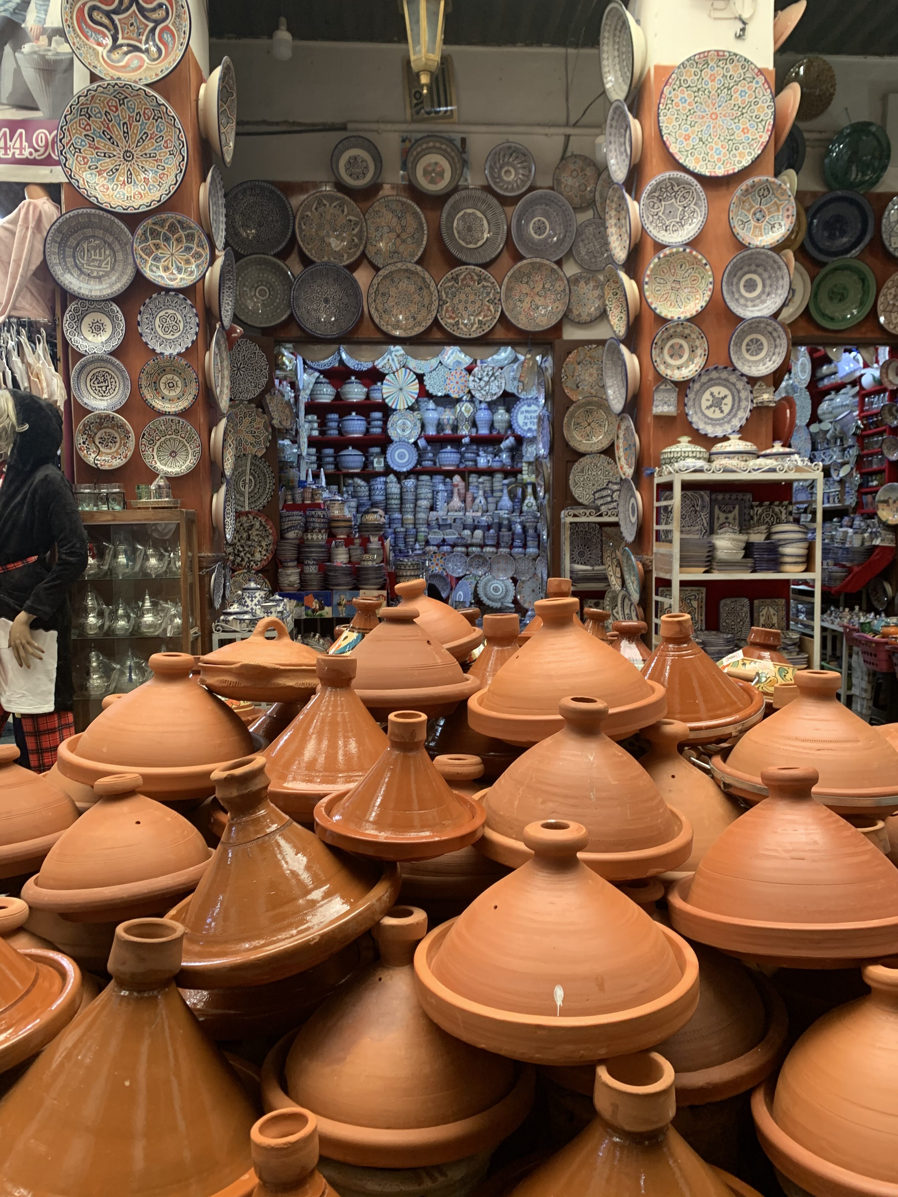 Pottery shop with Tagines in the front; lots of decorative plates and blowls on the walls.