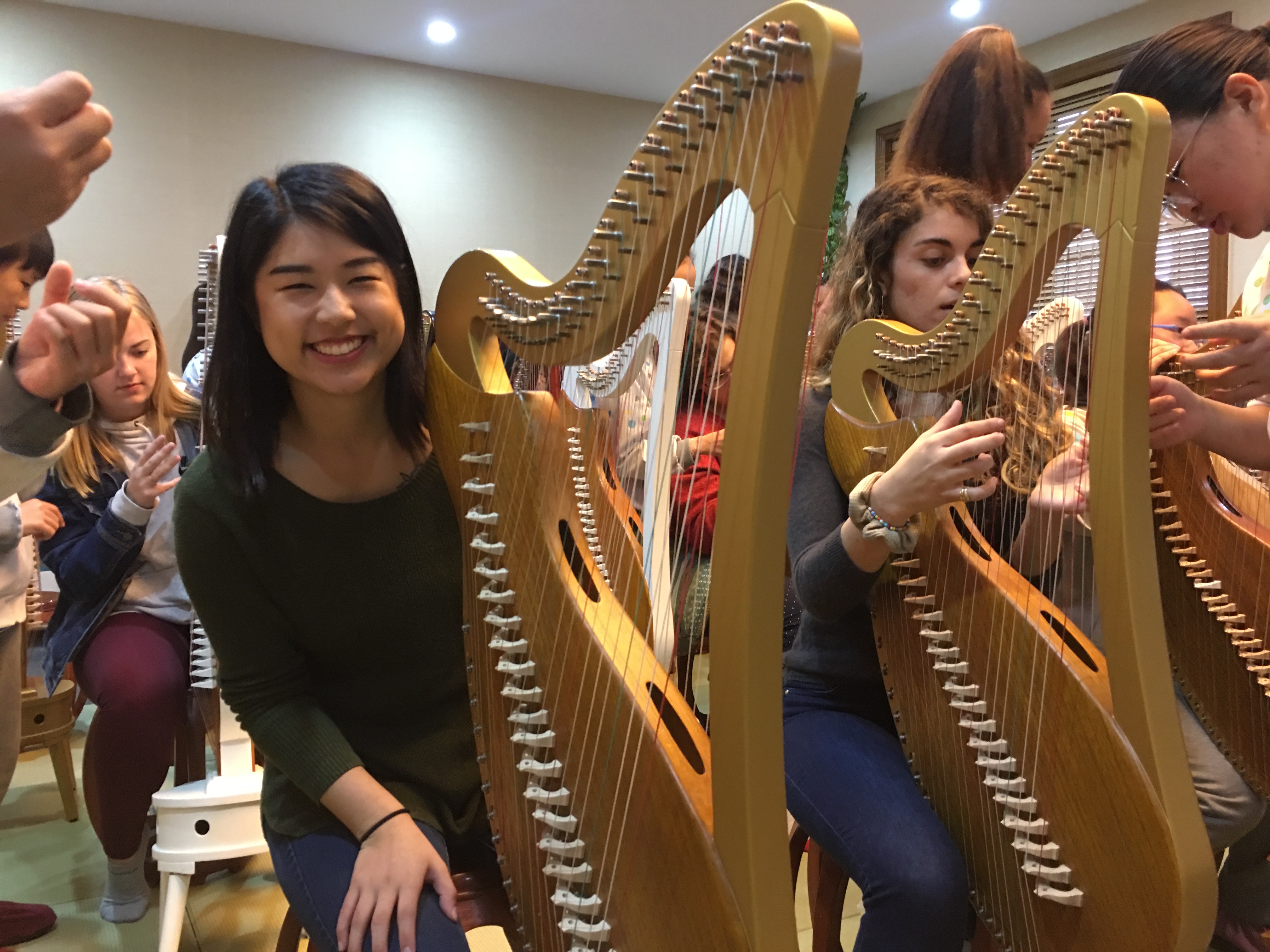 Student playing Chinese instruments resembling a large harp.
