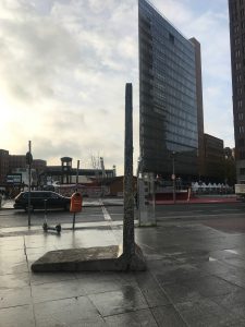single standing piece of Berlin wall with a skyscraper in the background