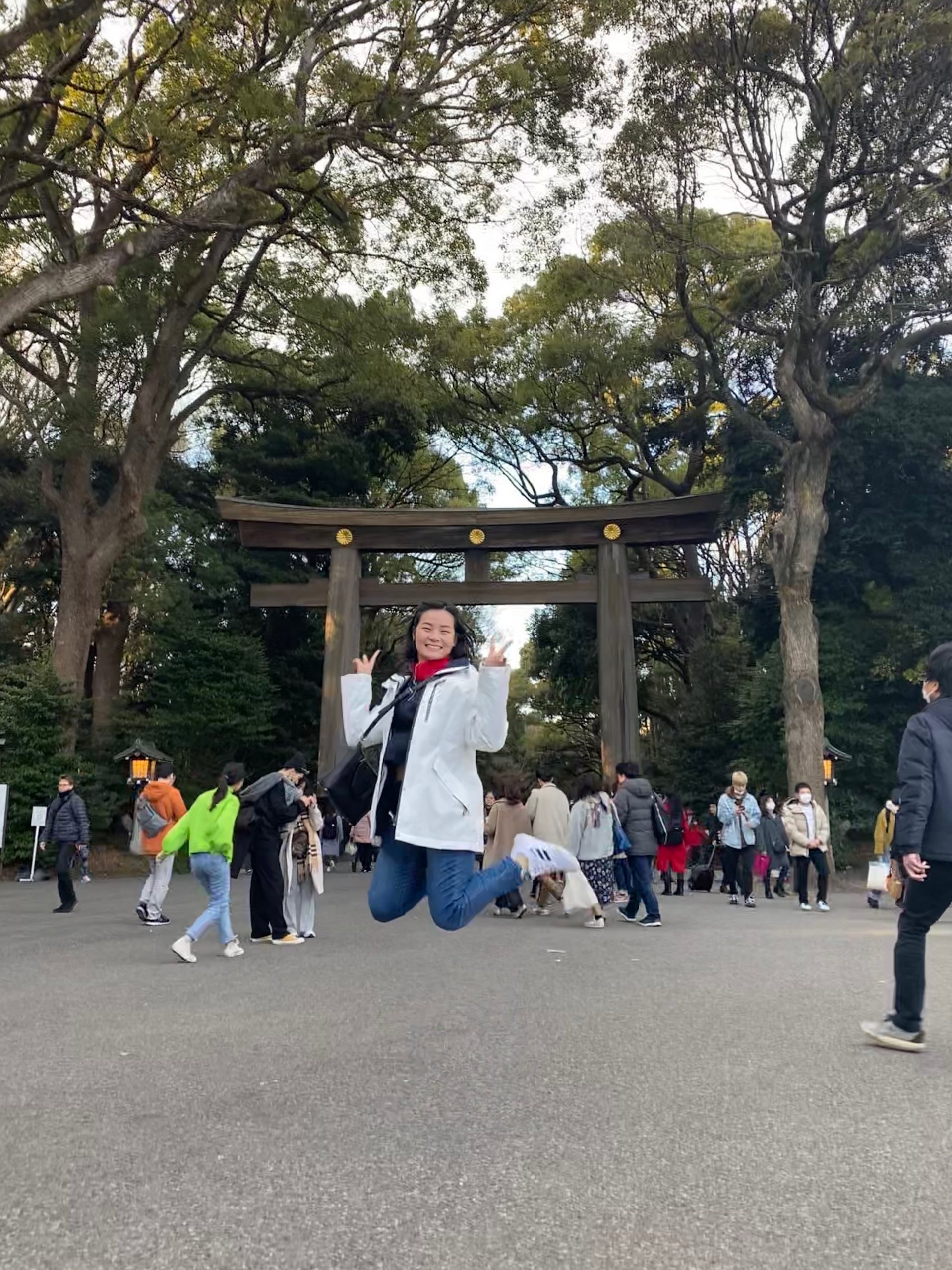 Me jumping and striking a pose in front of a wooden torii gate.