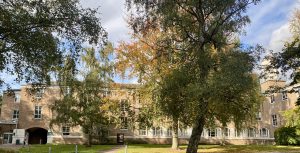 A brick building with fall coloured trees infront.