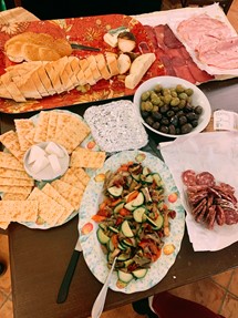bread, crackers, an assortment of meats and cheeses, olives, fruit salad, and sauteed vegetables.