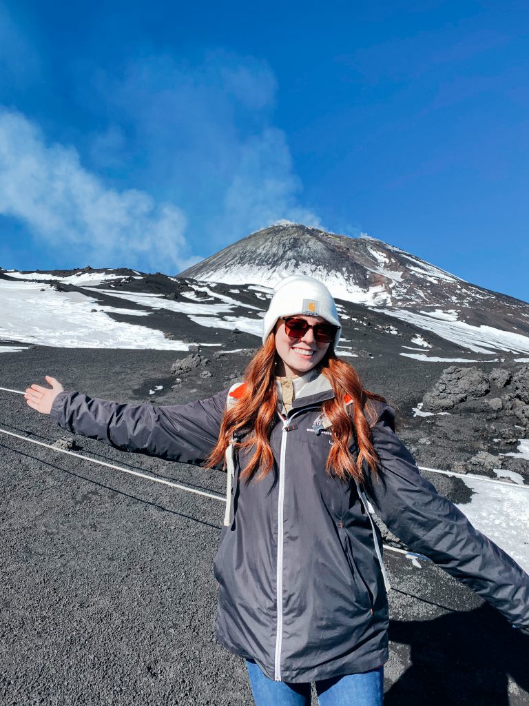 Student posing in front of snow-capped Mount Etna.