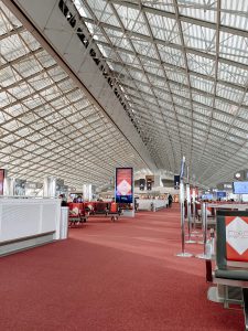 Bright red carpet flooded by morning sunlight streaming through the ceiling of windows in the Charles De Gaulle airport in Paris. 