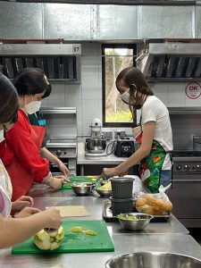 Pictured are students in aprons cutting up veggies in a kitchen