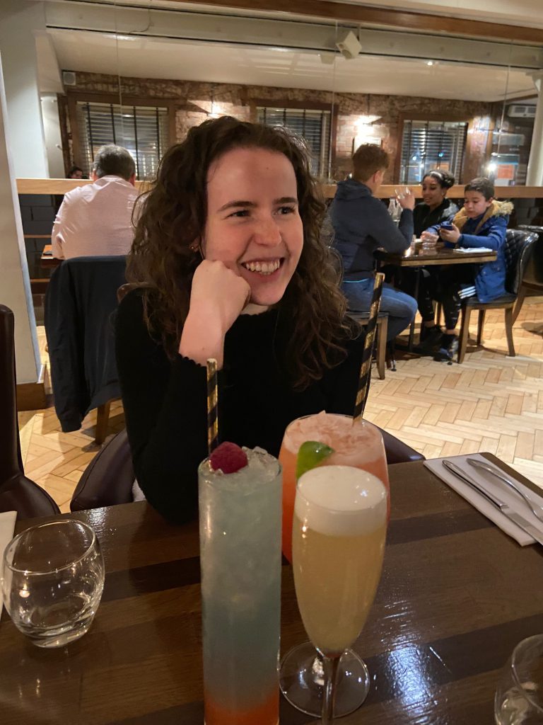 Three drinks on a table with smiling girl on opposite side of the table