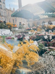 Bright yellow flowers surrounded by other bouquets in a market setting.