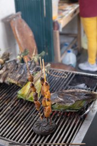 pictured are worms frying on a grill and they are on a stick