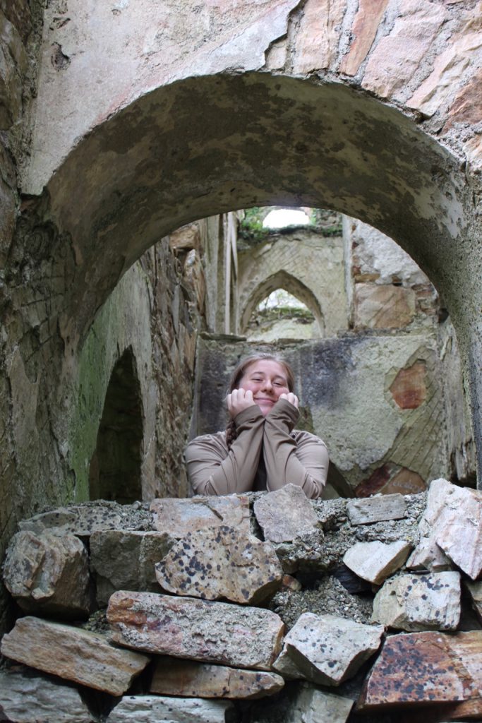 old castle walls and inside window with girl posed in the windowsill looking at the camera