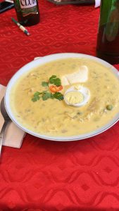 Pictured is a bowl of soup that is a creamy texture and yellow color with boiled eggs on top