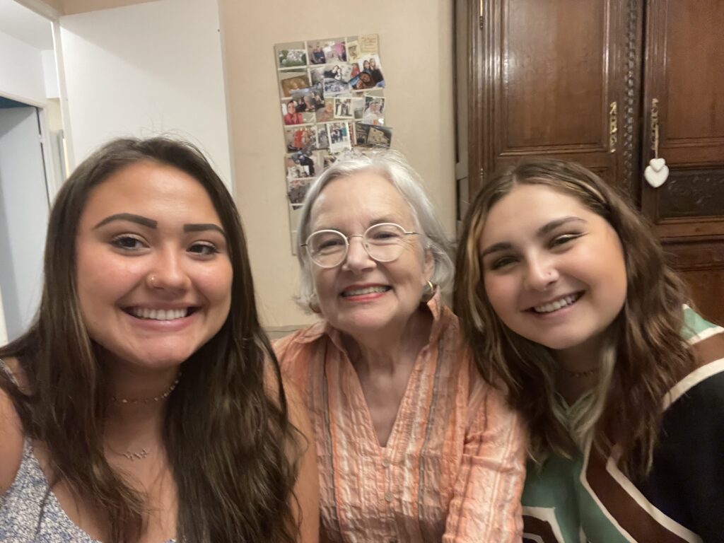 2 young women sitting on either side of an elderly women all smiling. 