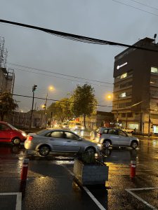 pictured is a rainy dark street with cars driving by
