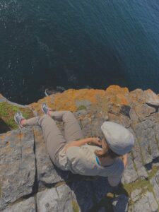 Legs thrown over the side of the cliff as I look out at the sea and the distance down to the water