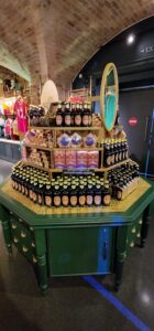A large, green and gold octagonal display covered in bottles of butterbeer, along with some other sweets from the Harry Potter franchise.