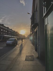 Sun setting on a random street in Dublin, with a car driving by