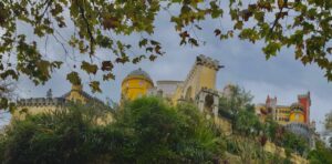 A short pano of Pena Palace, with tree branches framing the yellow fortress