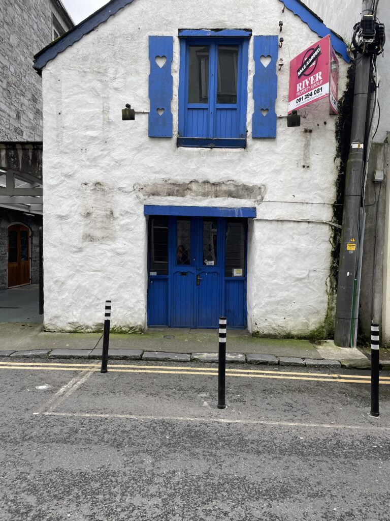 a white building with a blue door and a blue shuttered window
