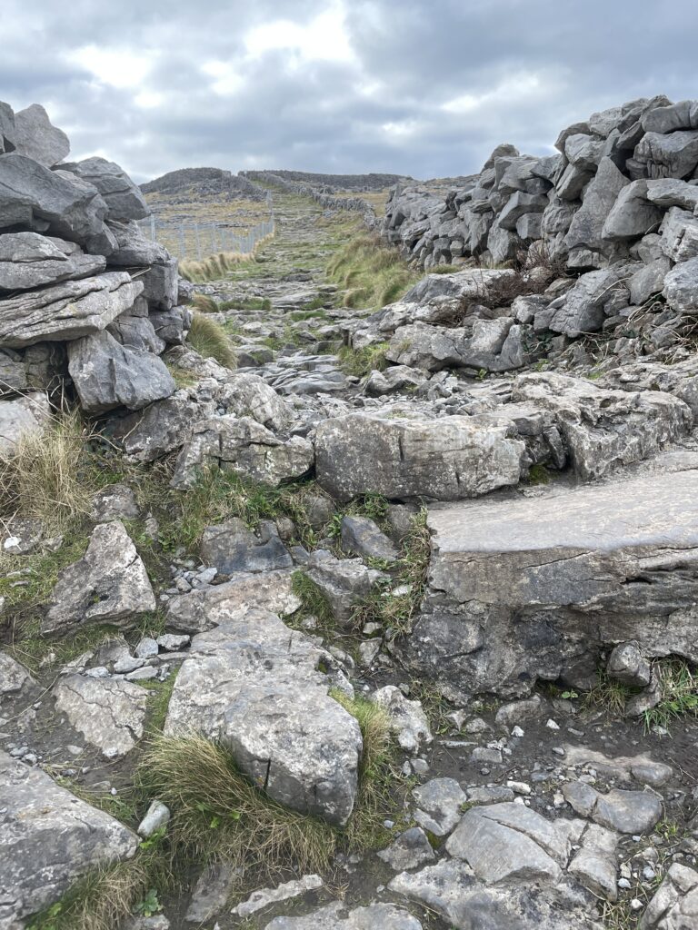 a rocky uphill path with stone walls on either side
