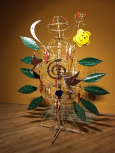 This is another artwork found in the contemporary art museum. It is of a wire person attached to leaves, birds, the sun, and the moon. This artwork is an Indigenous piece.