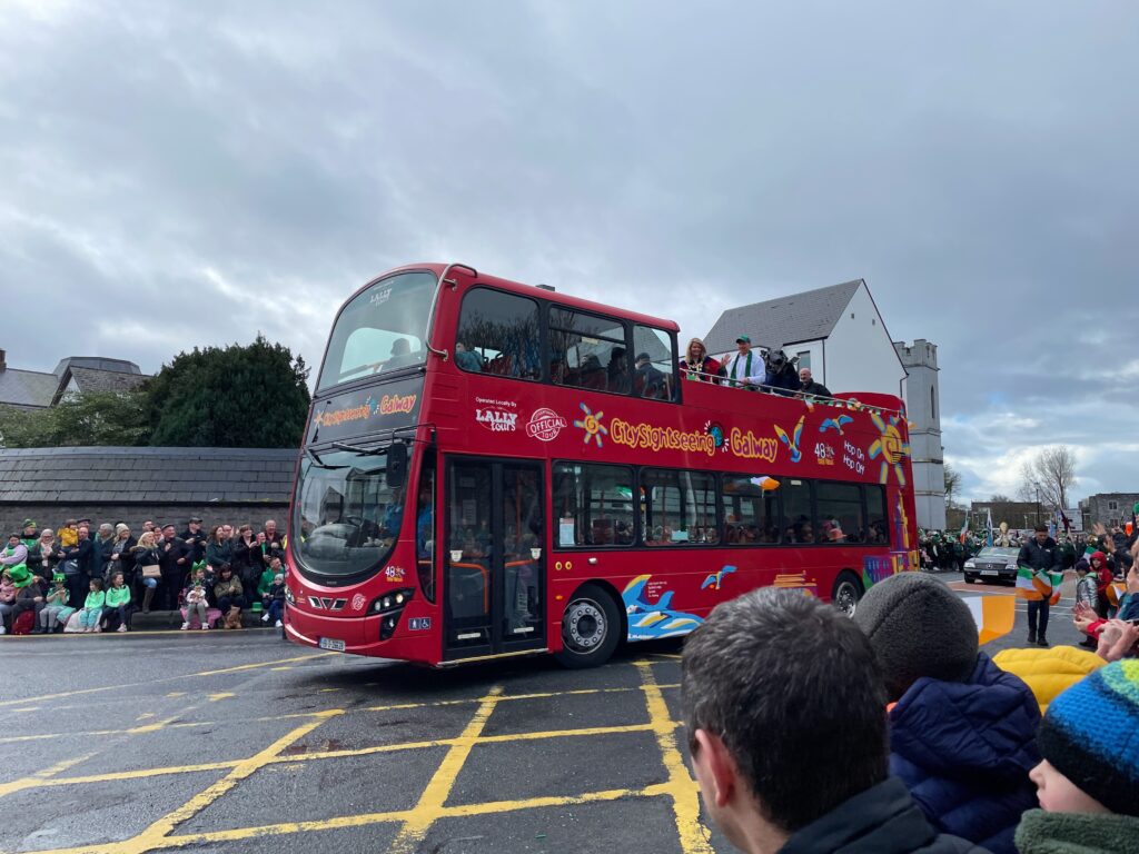 a red double decker bus with people standing on top