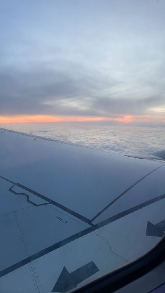 picture of a plane wing with the sunrise behind it