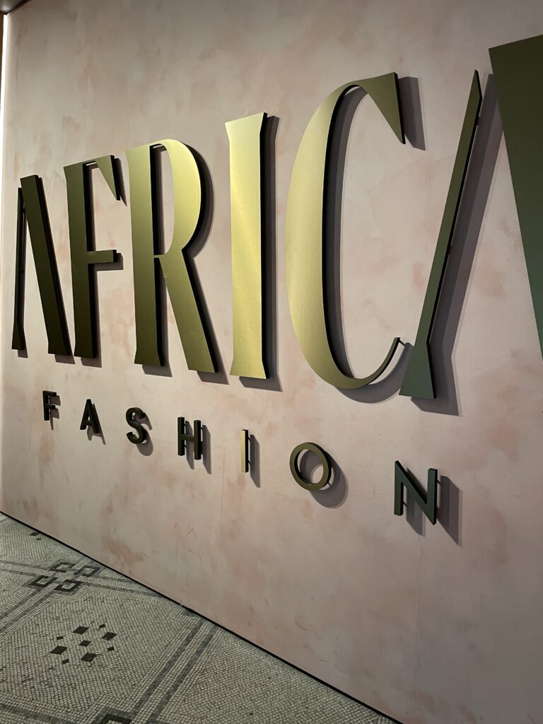 gold letters on a pink marble background, spelling "Africa; fashion"
