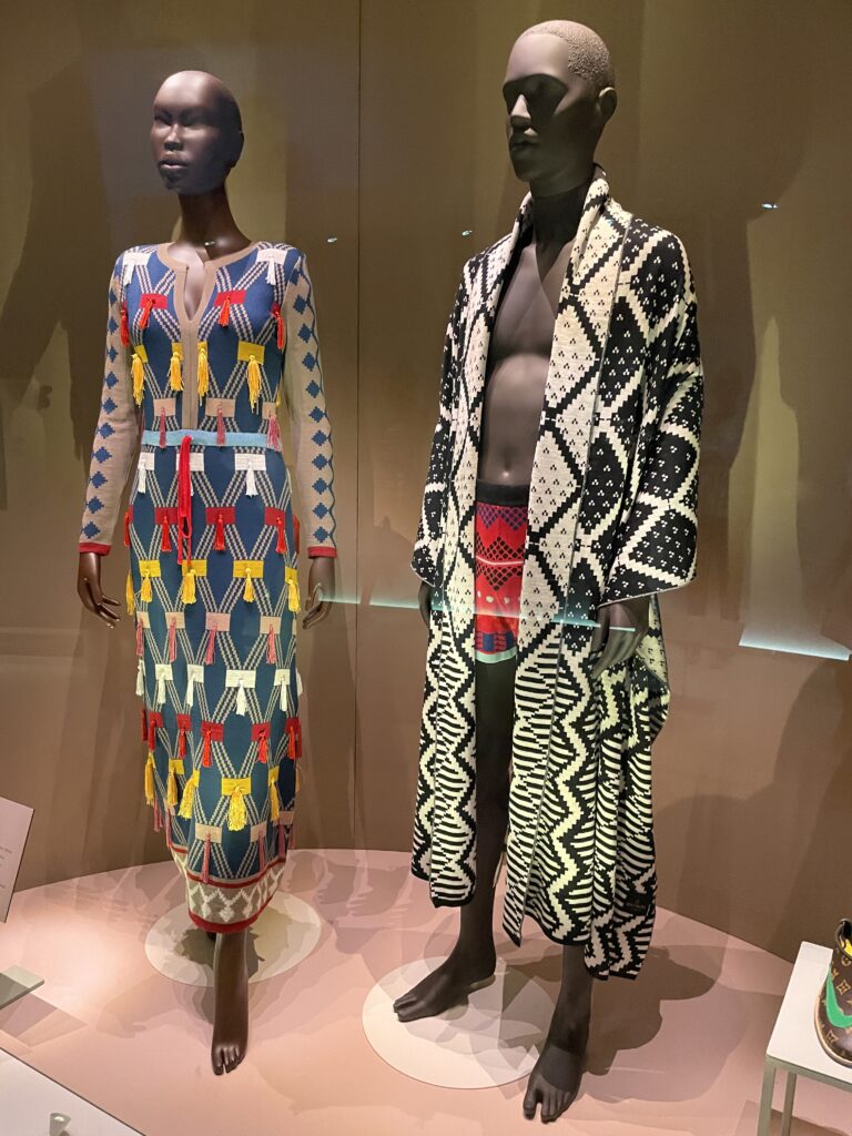 two mannequins: a rainbow colored long sleeved dress on the left mannequin, a black and white patterned coat on the right mannequin