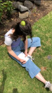 Pictured is me sitting on the grass and writing in a notebook. As I am doing this, a green apple is falling from a tree and appears to hit my head. This was a photographic class project for my Language and Cinema class.