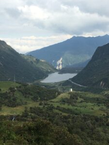 Pictured is another lake that is present in rural Ecuador. This is a far-away picture, which shows the small green hills leading to the lake itself, which is surrounded by nearby rock mountains. 