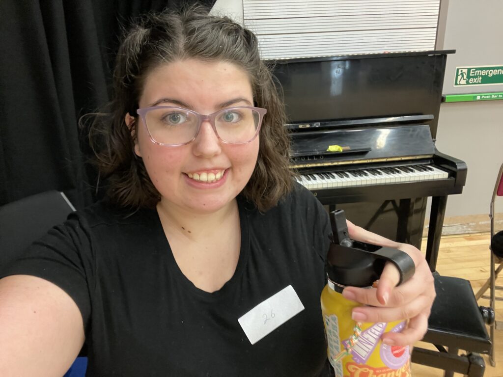 Katie. a girl with glasses and hair pulled half up and half down, holding a yellow water bottle