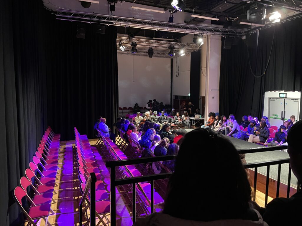 rows of chairs set up for a fashion show. purple stage lights shining on the seats