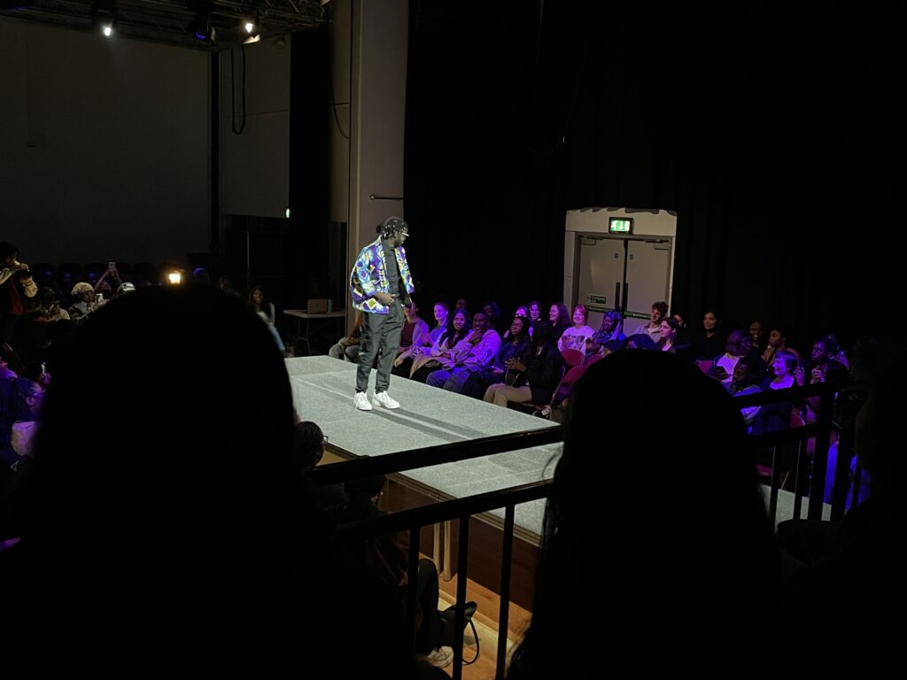 a man in a blue jacket and black pants walking the runway