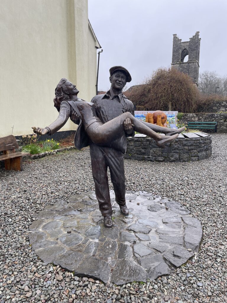 a statue of John WAyne holding a woman