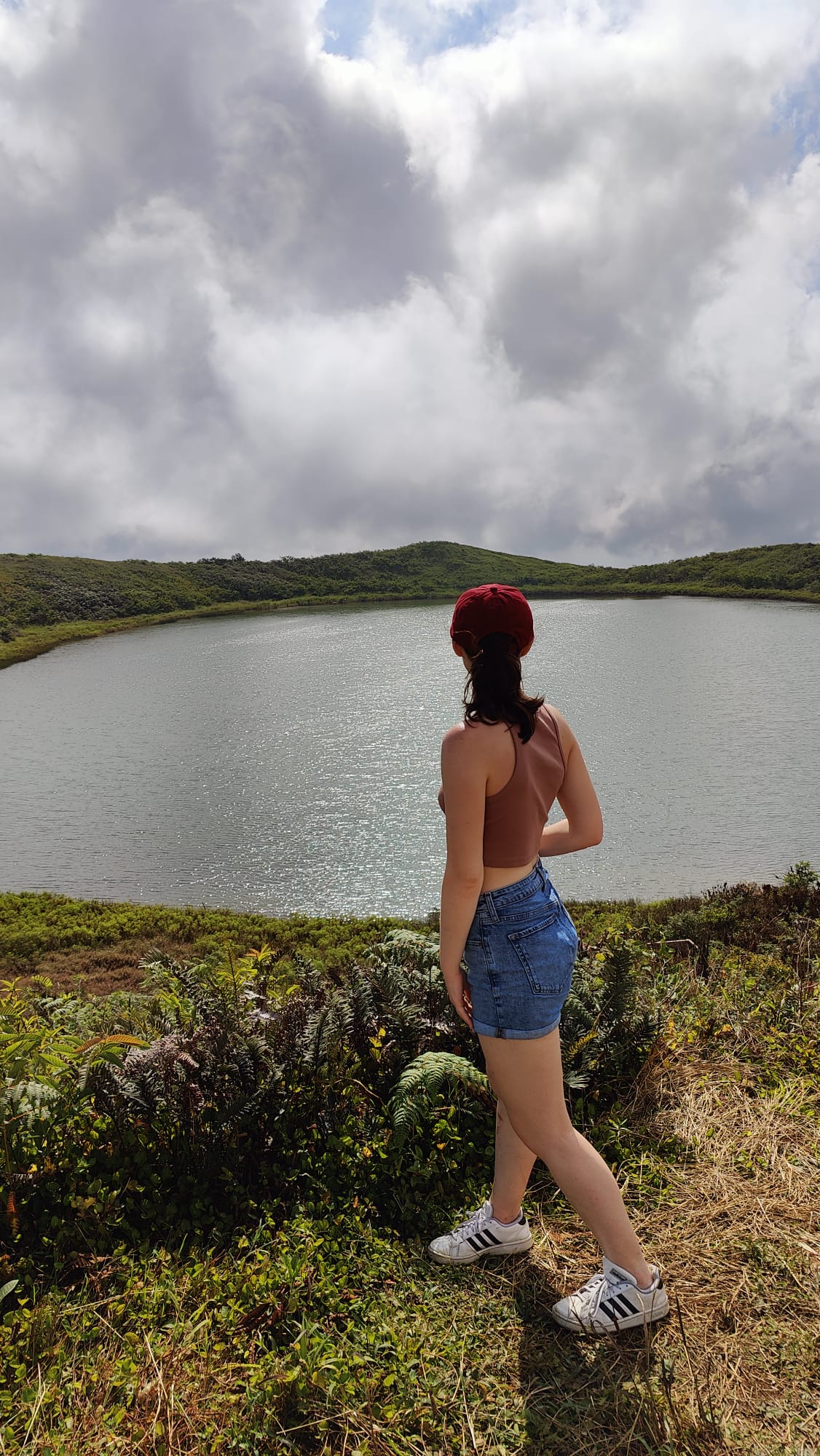 Pictured is me looking at El Junco, which is the fresh-water lake. The lake itself is a grey color, but with a cloudy sky above it. 