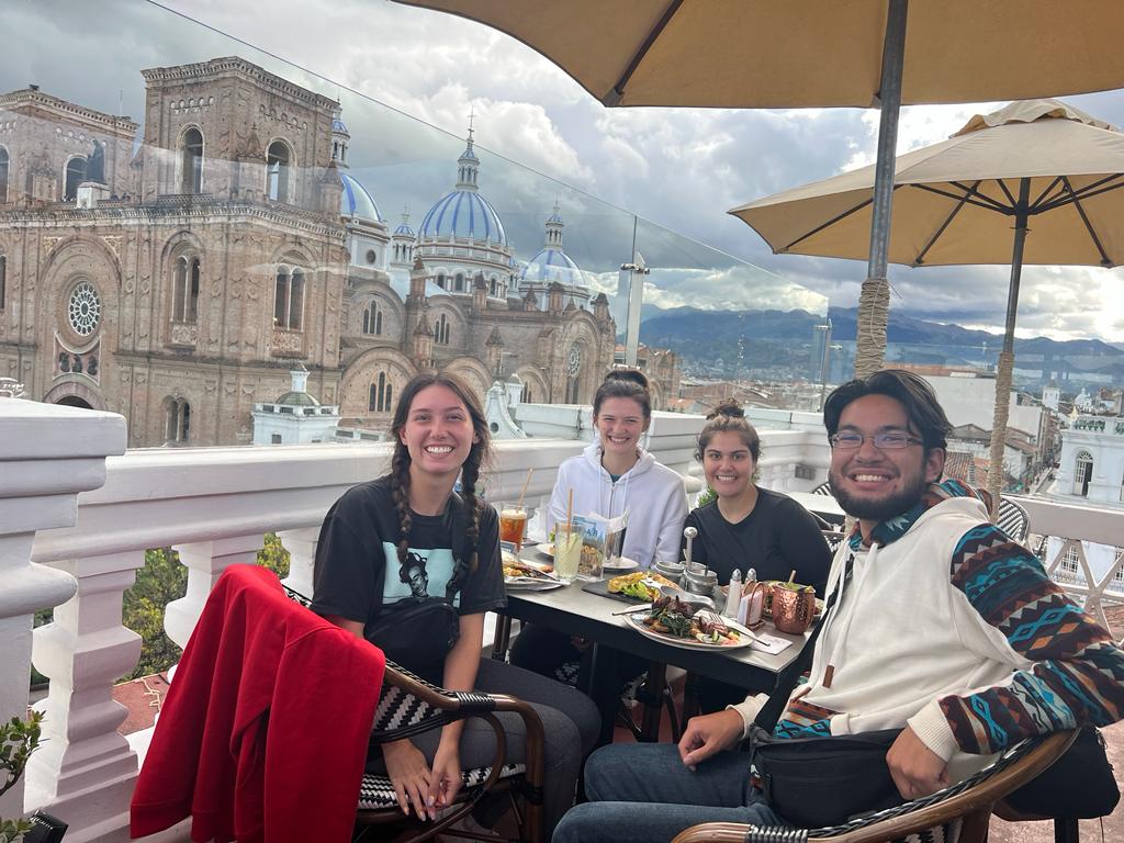 Pictured here is three friends and I eating dinner in Cuenca. We went to Negroni, which has rooftop sitting. In the photo, older buildings can be seen in the background.