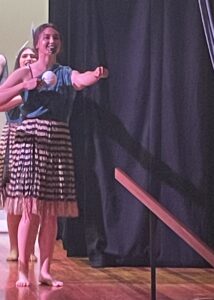 Kahiau dancing on stage with poi in right hand