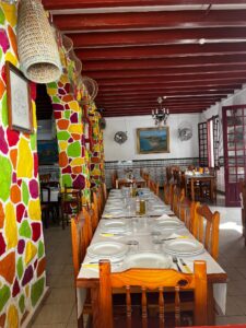 A colorful restaurant in TABARCA with a very long table lined with chairs.