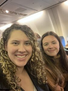 Clara and Elizabeth seated side by side on an airplane from Nottingham to Rome before takeoff 