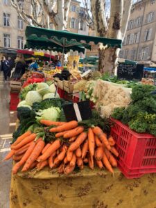 Market stand for veggies picturing bundles of carrots, broccoli, cabbage, etc. 