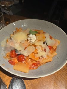 Image of a plate of pasta with tomatoes, sliced parmesan and ricotta.