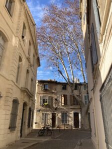 Image of a street in Avignone city center with buildings on either side and one in view down the center