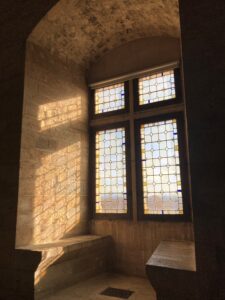 Image of the sun coming through the window in the Palais des Papes with stone benches on either side of the window