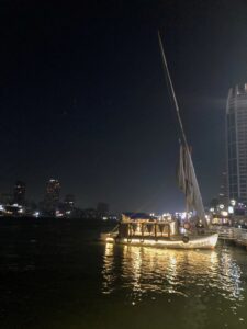 Image taken at night of the river Nile with a sailboat lit up.