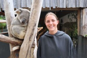 Koala sleeping in tree with girl standing next to it