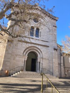 Local Church in Cassis with tree limbs coming out from the left side of the frame. The church is made of white stone with an arched doorway and windows above.