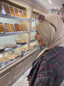 Profile of Nada picking out Ramadan desserts in a pastry shop.