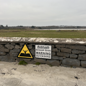 sign warning passerby peoples of quicksand in both English and Irish