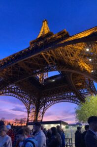 View looking up from under the Eiffel Tower at sunset with a pink sky in the background.
